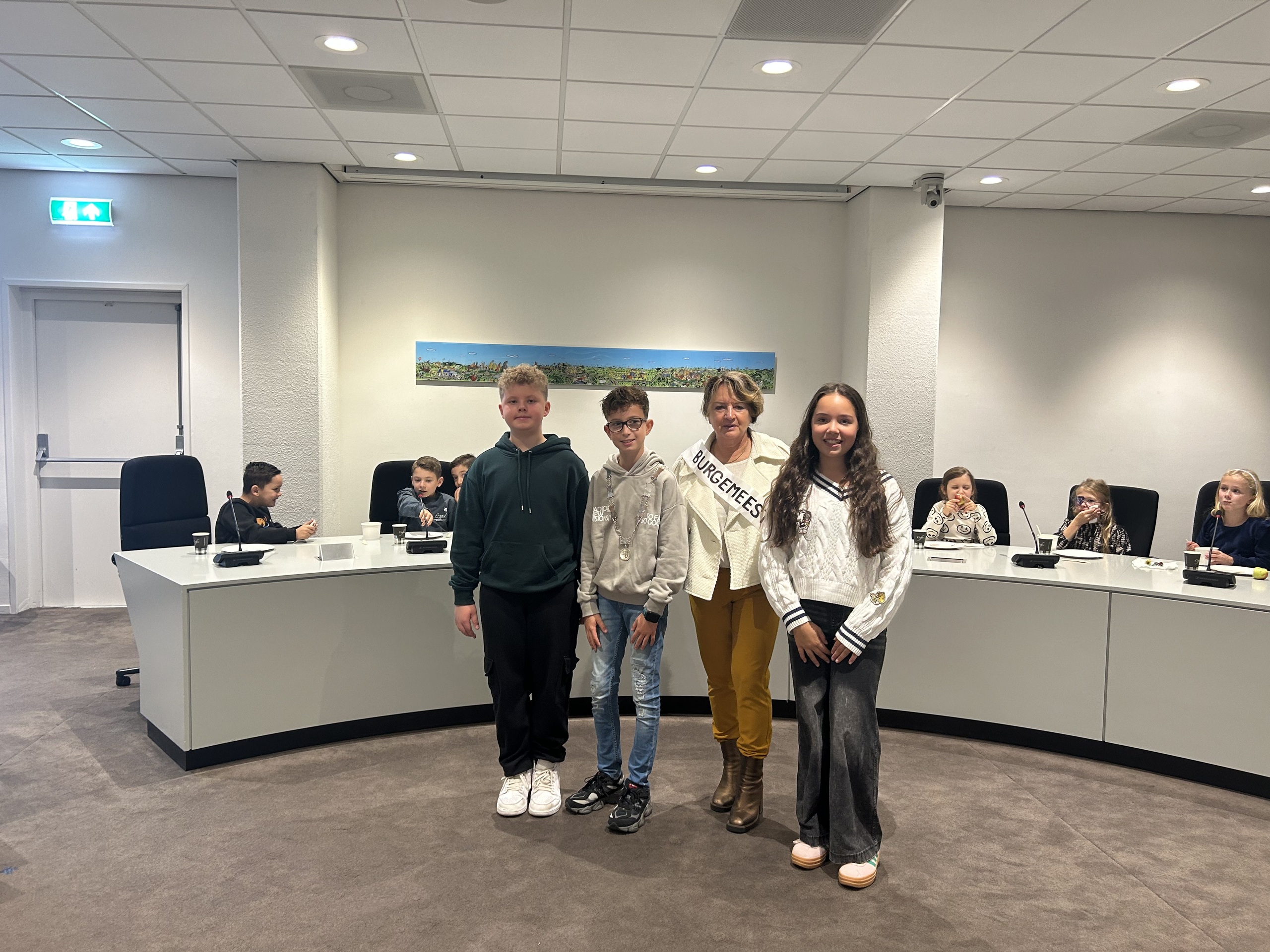 Groepsfoto van burgemeester Wilma van der Rijt, kinderburgemeester Jurre en kinderraadsleden Milah en Noël tijdens het burgemeesterontbijt in de Raadzaal