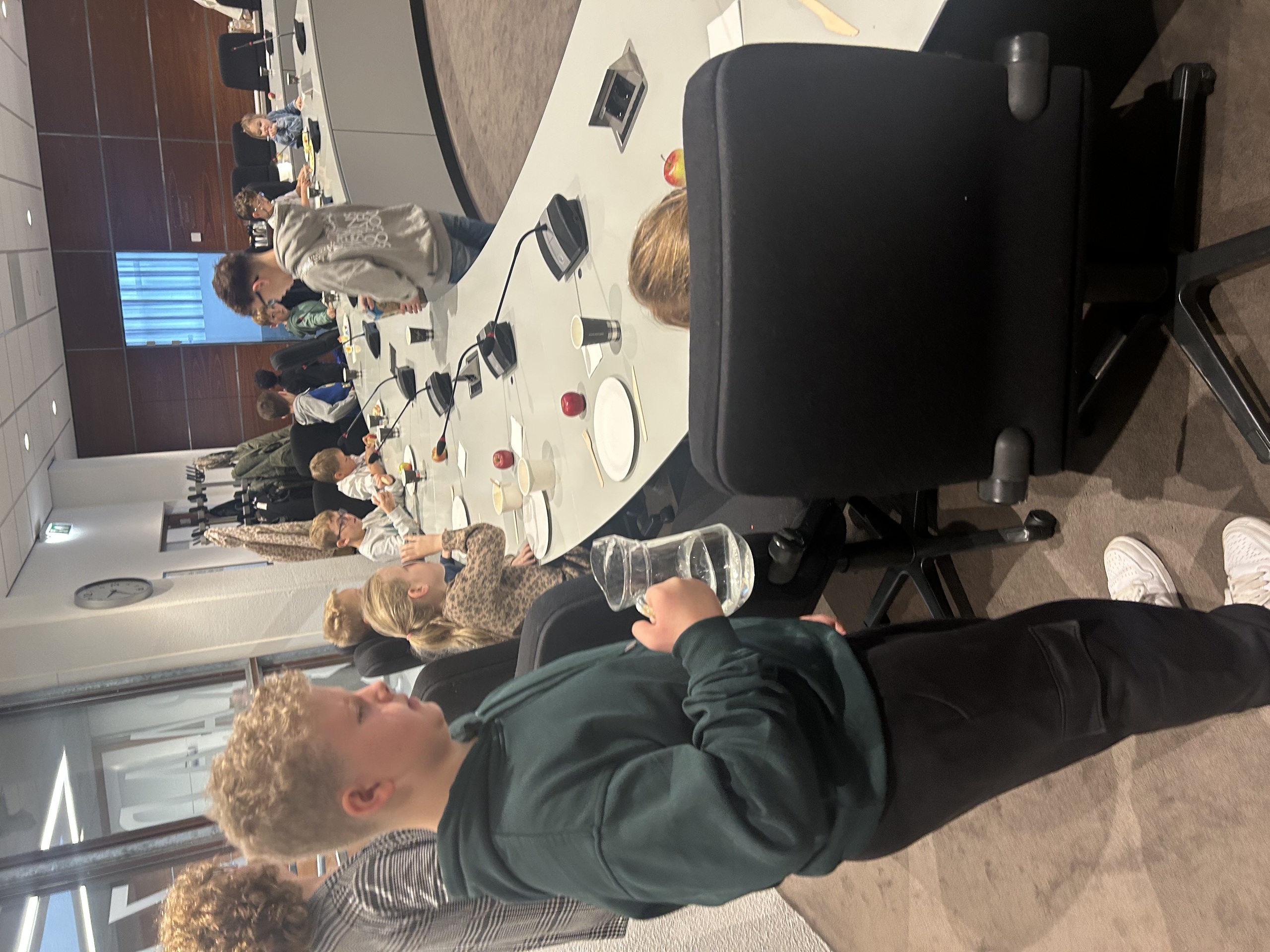 Kinderraadslid Noel Mulder serveert water tijdens het burgemeestersontbijt in de Raadzaal