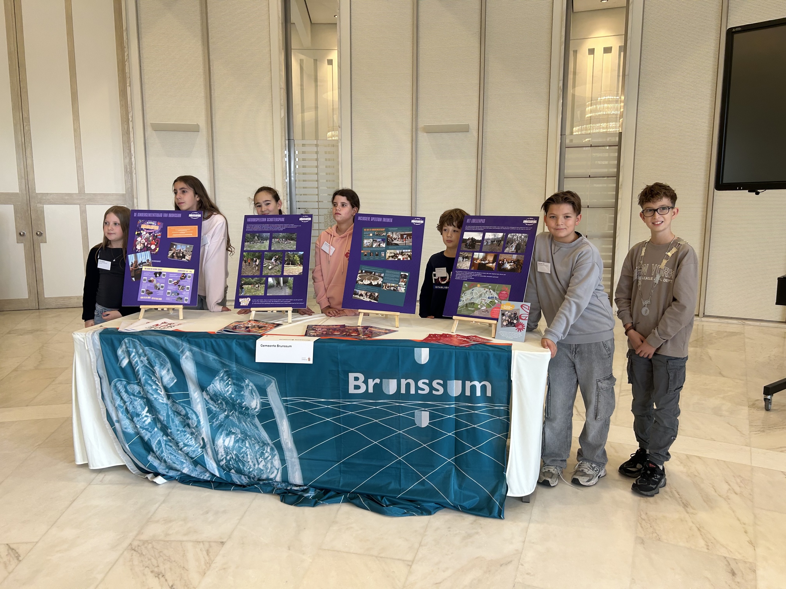 Leden van de kindergemeenteraad presenteren hun ideeën en initiatieven via een stand op de Limburgse Kinderbestuurdersdag in het Gouvernement in Maastricht