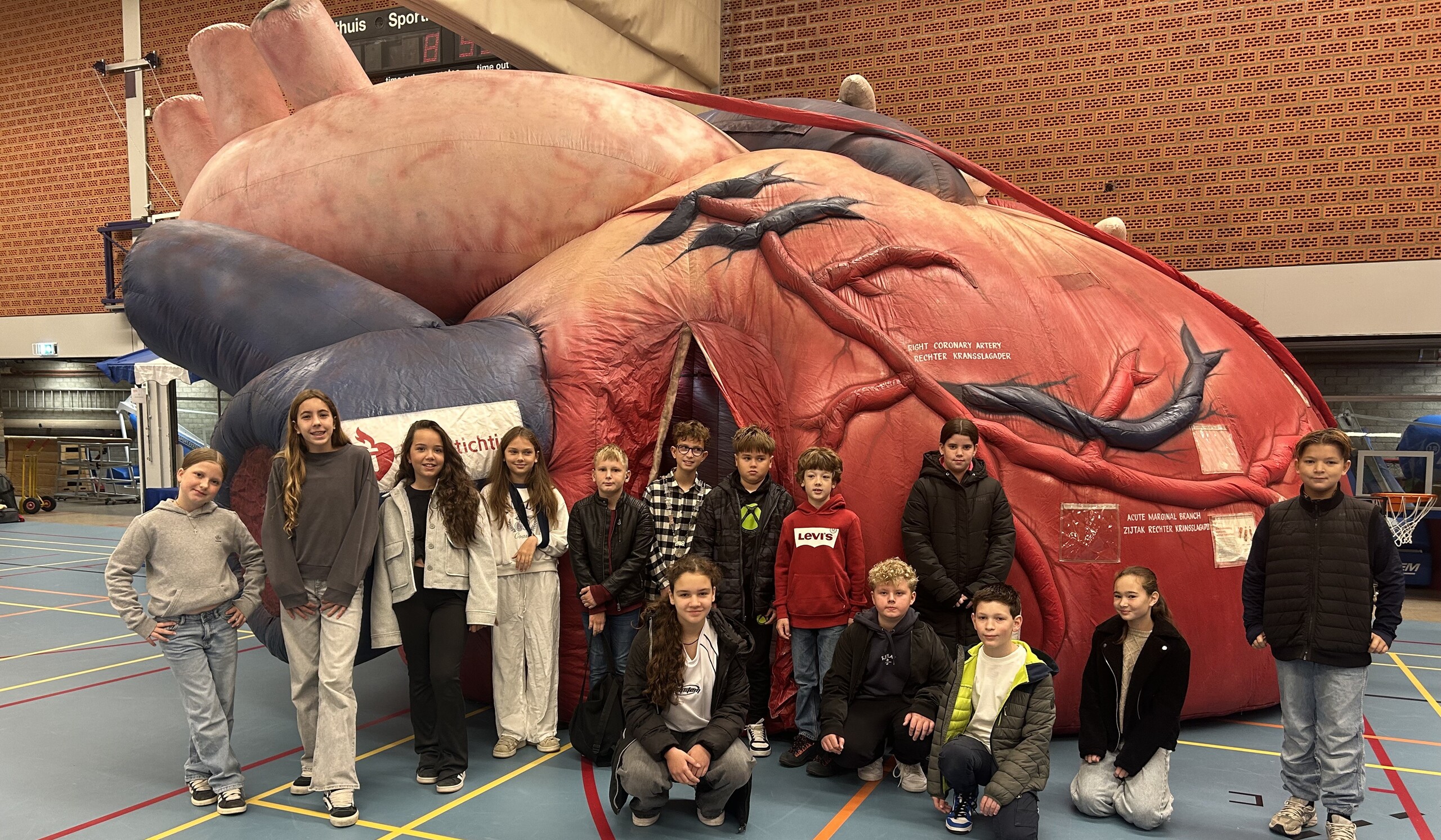 Groepsfoto kindergemeenteraad voor groot opblaasbaar hart tijdens reanimatie-estafette in Sporthal Rumpen 2025